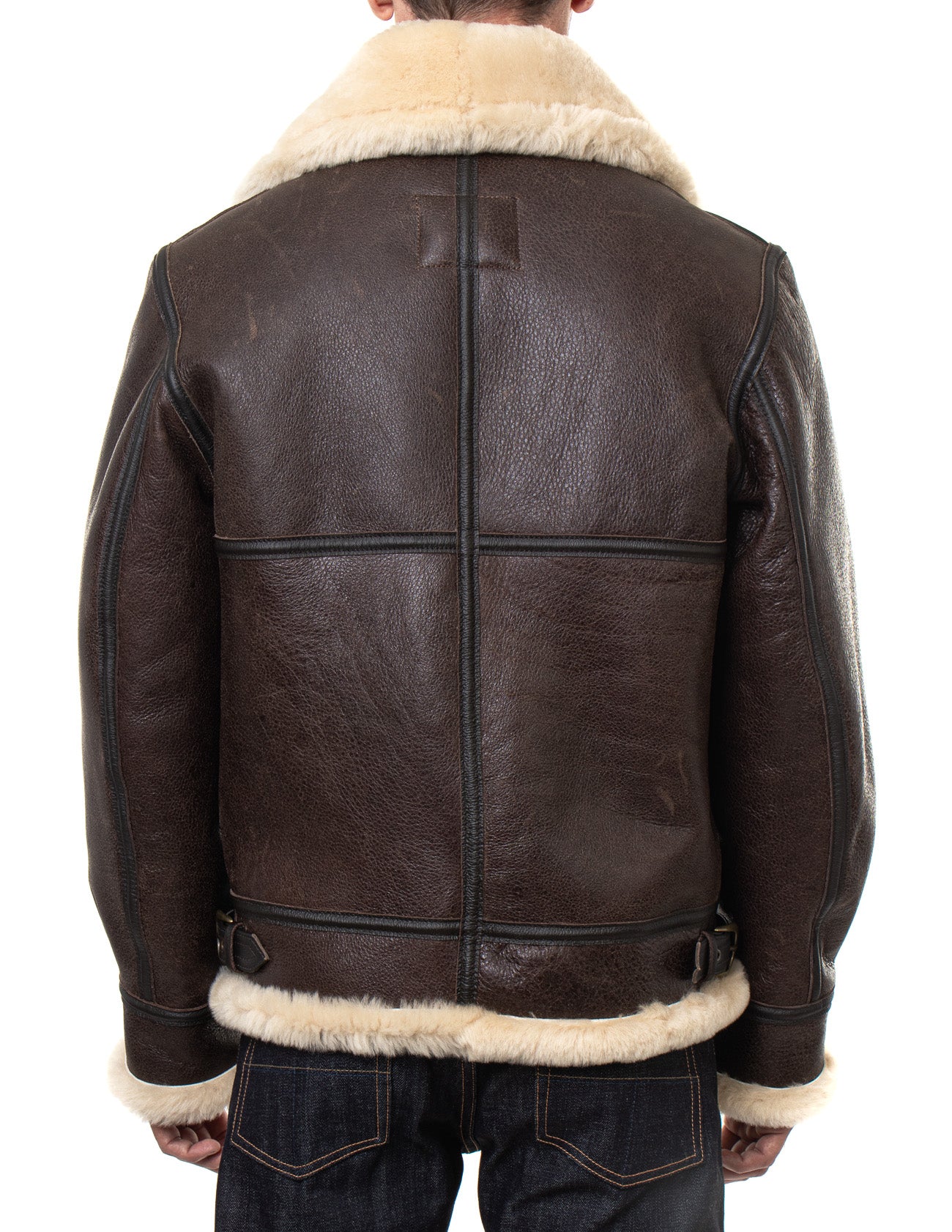 Back view of sheepskin shearling jacket on model with full, cream fur-lining and collar,  dark cross-stitching on the back